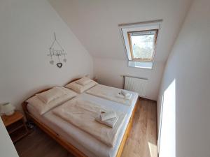 een slaapkamer met een bed met witte lakens en een raam bij PLÁZS Apartman Balatonlelle in Balatonlelle