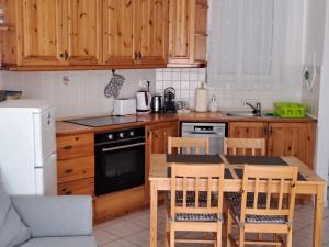 a kitchen with wooden cabinets and a table and chairs at Plázs Apartman Balatonlelle in Balatonlelle
