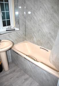 y baño con bañera y lavamanos. en XB Property - Comfy house perfect for families contractors relocators, en West Bromwich