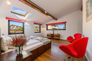 Sun Villas Accommodation Brasov في براشوف: غرفة نوم بسرير وكرسيين احمر