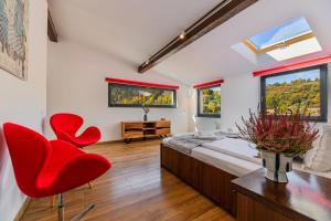 a bedroom with a bed and two red chairs at Sun Villas Accommodation Brasov in Braşov