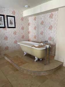 eine Badewanne im Bad mit Blumentapete in der Unterkunft The George Inn in Hatherleigh