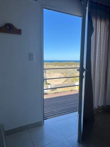 a door to a room with a view of the beach at Patagonia Lodges in Puerto Pirámides