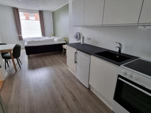 a kitchen with white cabinets and a bed in a room at Go Sleep Vandel in Vandel
