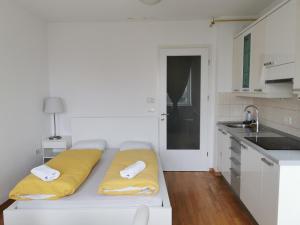Una cocina blanca con una cama con almohadas amarillas. en Trnovo apartment with free parking, en Liubliana 5 fotos más