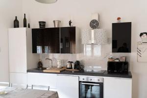 cocina con armarios blancos y encimera negra en Grazioso appartamento a due passi dal mare, en Minturno