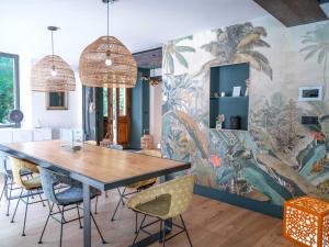 a dining room with a table and chairs and a mural at La Maison du Bonheur - Grande Piscine & Terrasse in Brens