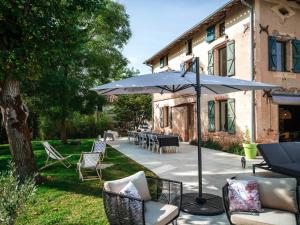 een patio met een parasol, stoelen en een tafel bij La Maison du Bonheur - Grande Piscine & Terrasse in Brens