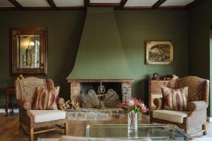 sala de estar con chimenea, sillas y mesa en The Hawthorn Boutique Hotel, en George