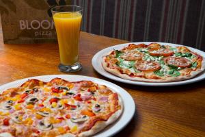 twee pizza's op borden op een tafel met een glas sinaasappelsap bij Royal National Hotel in Londen