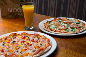 zwei Pizzen auf Platten auf einem Tisch mit einem Glas Orangensaft in der Unterkunft Royal National Hotel in London