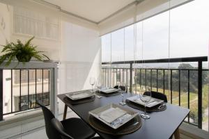 une salle à manger avec une table, des chaises et une grande fenêtre dans l'établissement My Home Studio - GRU, à Guarulhos