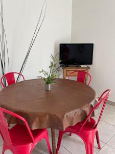 uma mesa de madeira com cadeiras vermelhas e uma televisão em Alquilo hermoso Departamento cerca de Chacras em Luján de Cuyo