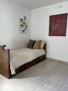 uma cama num quarto branco com uma pintura na parede em Alquilo hermoso Departamento cerca de Chacras em Luján de Cuyo