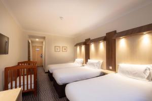 una camera d'albergo con tre letti e una culla di Royal National Hotel a Londra
