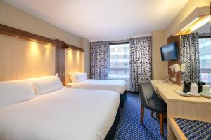 a hotel room with two beds and a desk at Royal National Hotel in London