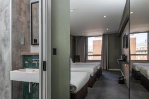 a hotel room with three beds and a sink at Royal National Hotel in London