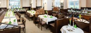 uma sala de jantar com mesas e cadeiras com toalhas de mesa brancas em Lübsche Thorweide em Wismar