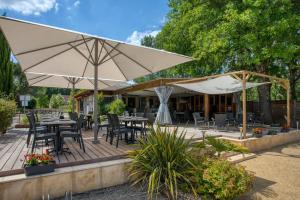 une terrasse en bois avec des tables, des chaises et des parasols dans l'établissement Camping du Lac de Grolejac, à Groléjac