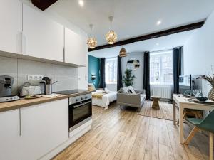 a kitchen and living room with white cabinets at L'Odyssée in Saint-Étienne +8 photos