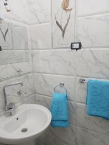 y baño con lavabo blanco y toallas azules. en Nubian Queen Guest House en Asuán