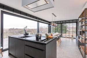 a kitchen with a large window and a large kitchen island at Whaaw Westende-bad in Middelkerke