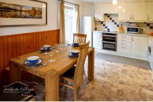 eine Küche mit einem Holztisch mit Stühlen und eine Küche mit weißen Schränken in der Unterkunft Lochside Cottage - near Aviemore in Aviemore + 2 Fotos