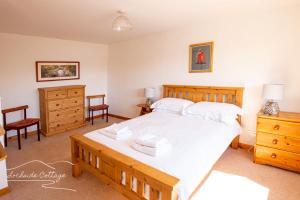 ein Schlafzimmer mit einem großen Bett mit weißer Bettwäsche in der Unterkunft Lochside Cottage - near Aviemore in Aviemore