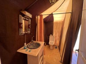 a small bathroom with a sink and a toilet at Roses desert camp in Merzouga