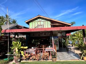 Somphamit Guesthouse في Ban Khon: مطعم فيه طاولات وكراسي امام مبنى