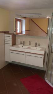 a bathroom with a white sink and a mirror at Loretz Luzia in Silbertal