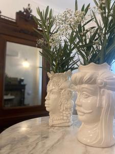 two white heads sitting on a table with a vase at Ortigia Twin Rooms in Syracuse