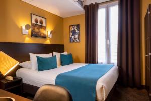 a hotel room with a large bed with blue pillows at Chatillon Paris Montparnasse in Paris