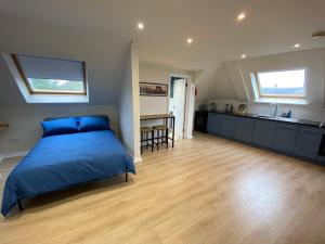 a bedroom with a blue bed and a kitchen at Lovely spacious loft close to train station in Worthing