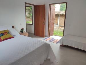 a white bedroom with a bed and a door to a yard at Casa do Artista in Trancoso