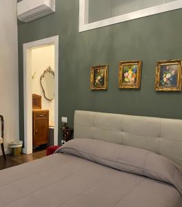 a bedroom with a bed and four paintings on the wall at Ortigia Twin Rooms in Syracuse