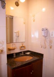 baño con lavabo, espejo y teléfono en Hotel Playa en San Clemente del Tuyú