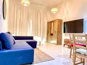 Calm&Cozy1BR- Dubai Silicon Oasis-15min-Dxb airpt في دبي: غرفة معيشة مع أريكة زرقاء وتلفزيون بشاشة مسطحة