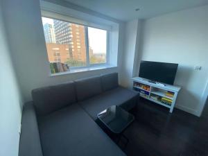 a living room with a couch and a flat screen tv at 1+1 Modern flat next to Sutton train station in Sutton