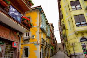 une ruelle étroite avec des bâtiments jaunes dans une ville dans l'établissement Bermeo Vintage Flat Ideal parejas, à Bermeo