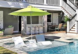 a green umbrella sitting next to a swimming pool at Luxury Modern Home- Steps 2 Beach, Private Pool/Bar, Sleeps 16, 7 BD-5.5 BR- 'The Lucky Penny' in Isle of Palms