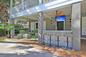 um pátio com um bar com bancos em frente a uma casa em Luxury Modern Home- Steps 2 Beach, Private Pool/Bar, Sleeps 16, 7 BD-5.5 BR- 'The Lucky Penny' em Isle of Palms