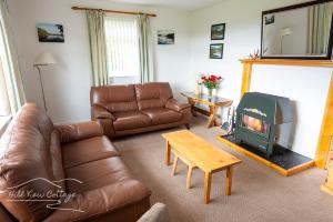 a living room with a leather couch and a fireplace at Hill View Cottage - near Aviemore in Aviemore