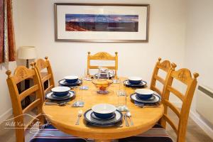 a wooden table with chairs and plates and bowls on it at Hill View Cottage - near Aviemore in Aviemore