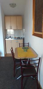 a kitchen with a table and chairs with a yellow table cloth at Apartment Matkovic in Tivat