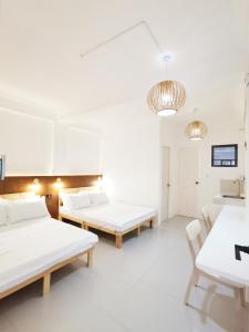 una stanza con due letti, un tavolo e delle sedie di NomadsMNL Airport Hostel a Manila