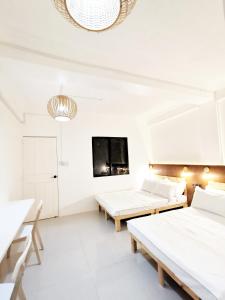 biały pokój z 2 łóżkami i telewizorem w obiekcie NomadsMNL Hostel w mieście Manila