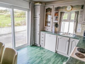 cocina con armarios blancos y ventana grande en Castle Demesne House, en Clifden