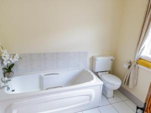 uma casa de banho branca com uma banheira e um WC em Castle Demesne House em Clifden