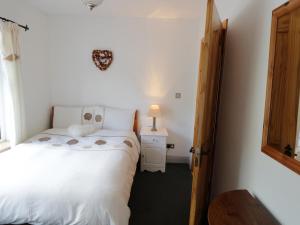 um pequeno quarto com uma cama branca e uma janela em Castle Demesne House em Clifden